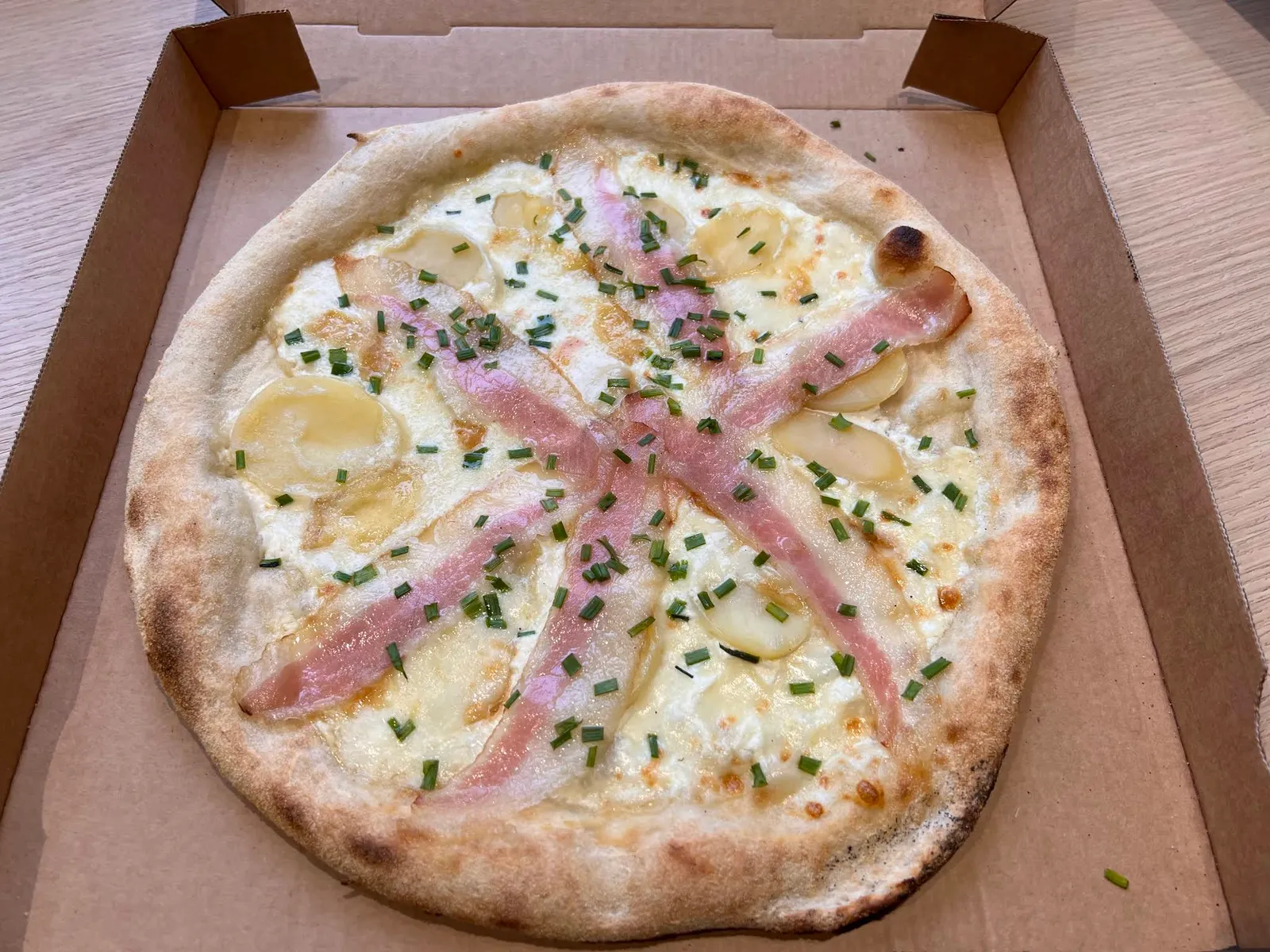 Pizza base crème au jambon, pommes de terre et ciboulette, dans sa boîte